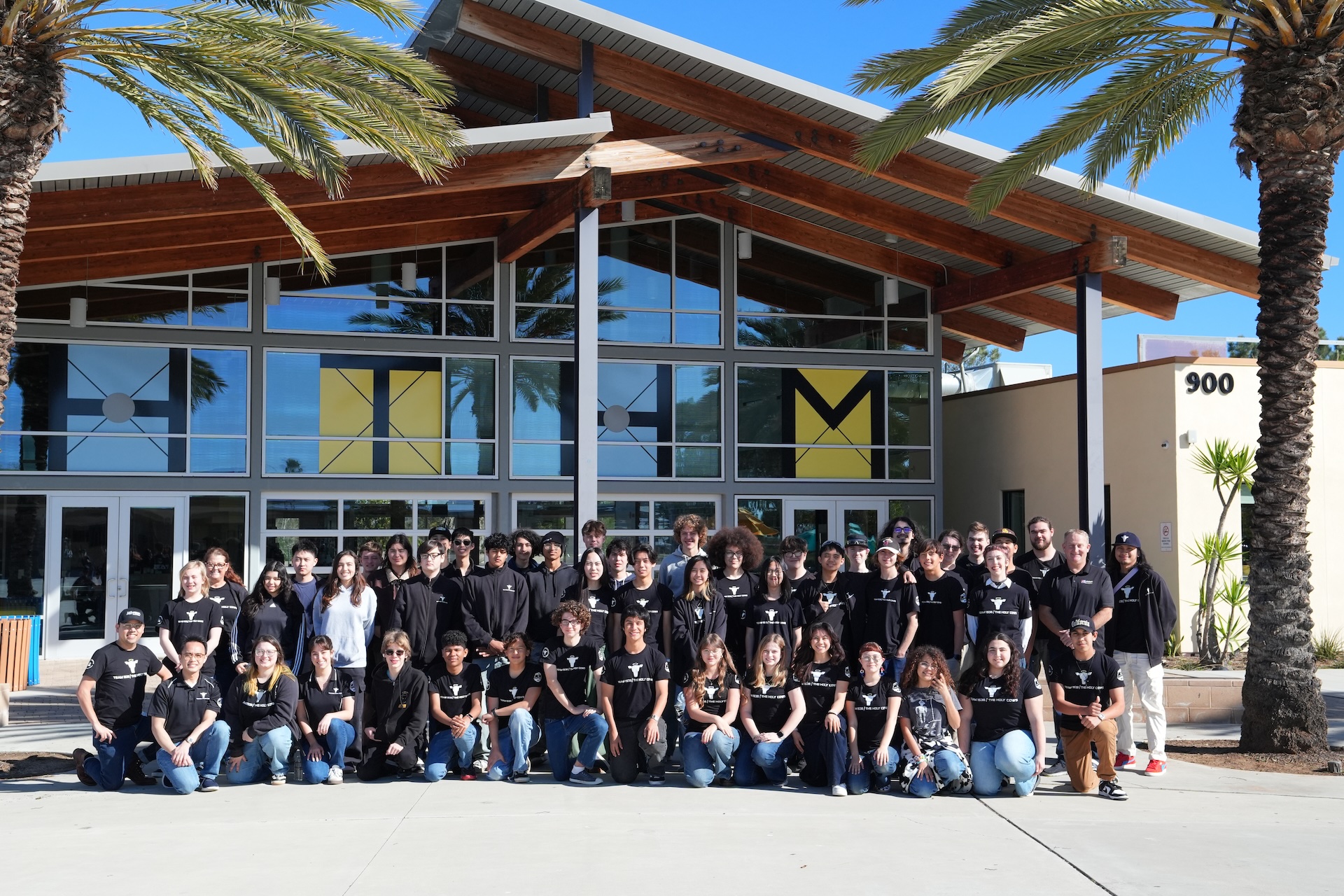 Team 1538 The Holy Cows posing in front of the school building